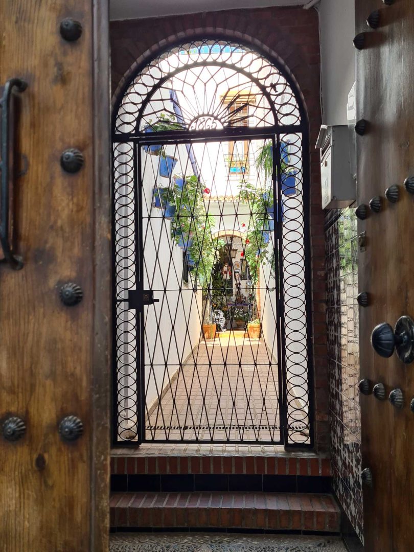 Gittertor mit Blick auf einen gepflegten Hinterhof in Córdoba – Wohnmobil-Rundreise Spanien