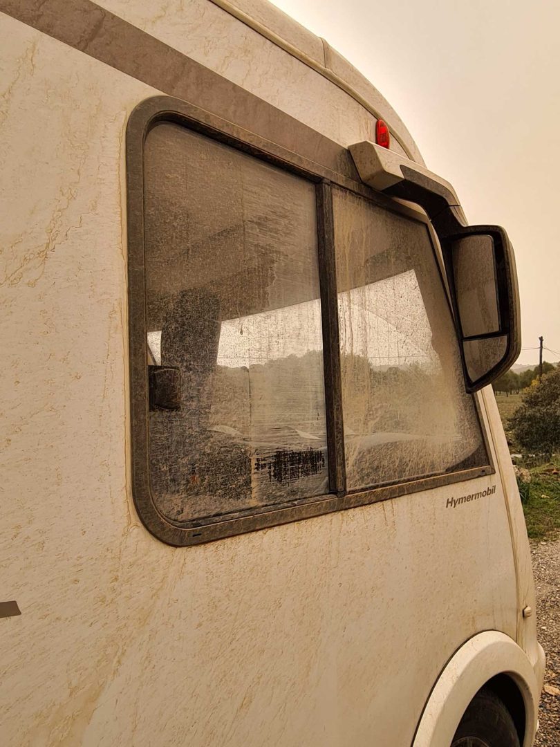 Unser Wohnmobil von der Seite, komplett mit rotem Schlamm bedeckt – sogar das Seitenfenster ist nicht verschont – Wohnmobil-Rundreise Spanien