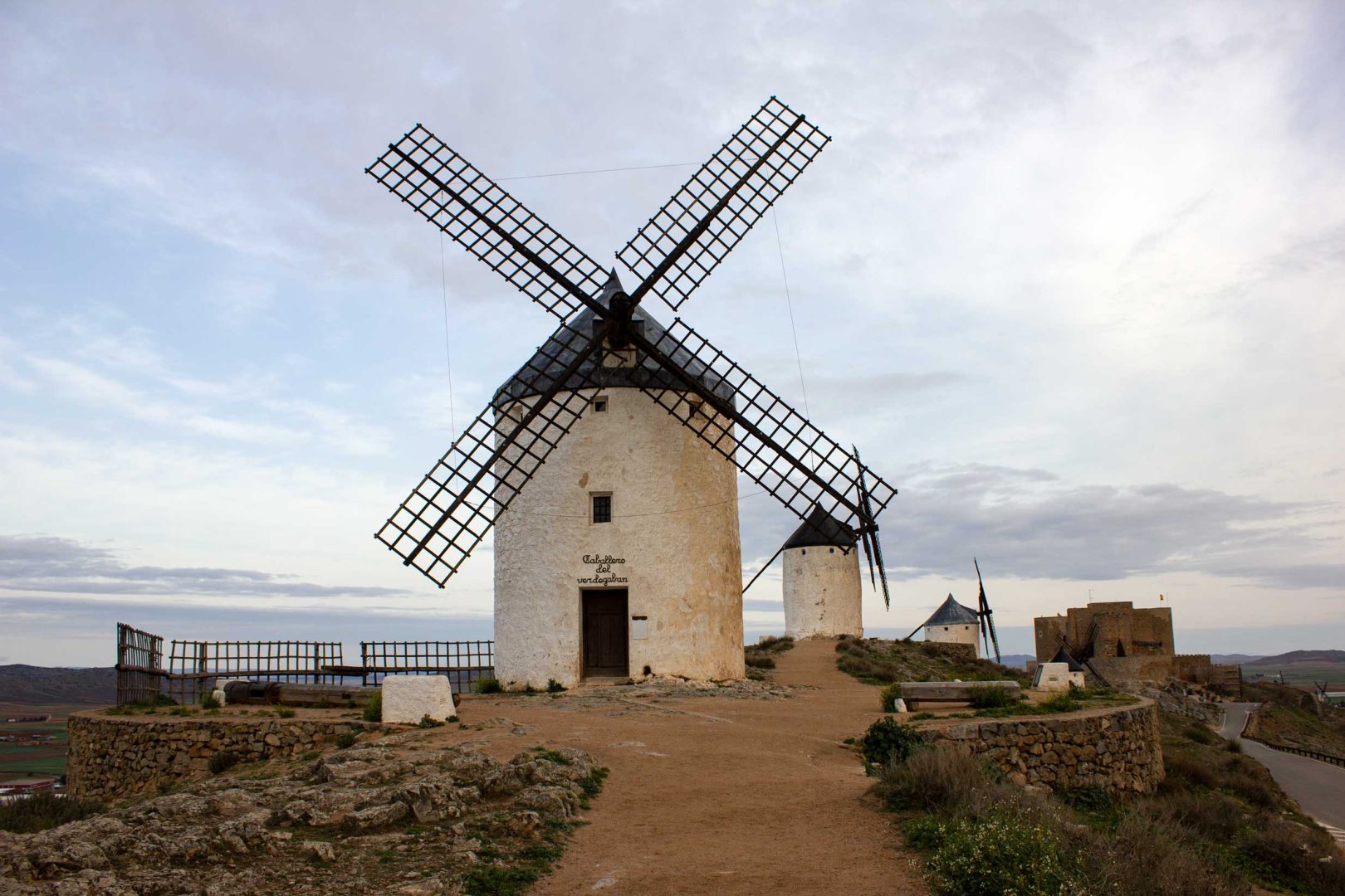 Vier Windmühlen auf dem Hügel, im Vordergrund die Windmühle Caballero del Verde Gabán, im Hintergrund das Kastell von Consuegra – Wohnmobil-Rundreise Spanien