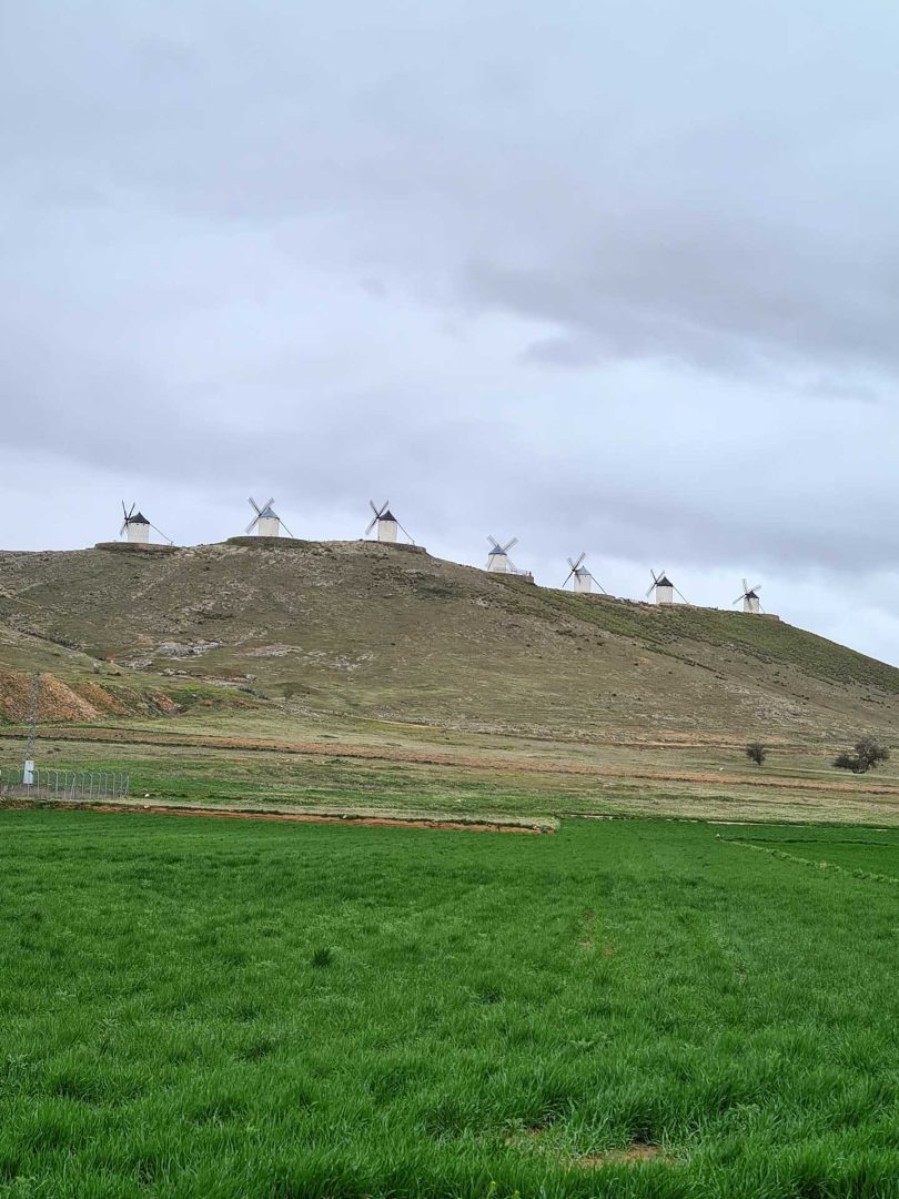 Sechs weiße Windmühlen thronen auf einem Berg und prägen die eindrucksvolle Landschaft – klassisches Don-Quijote-Panorama – Wohnmobil-Rundreise Spanien