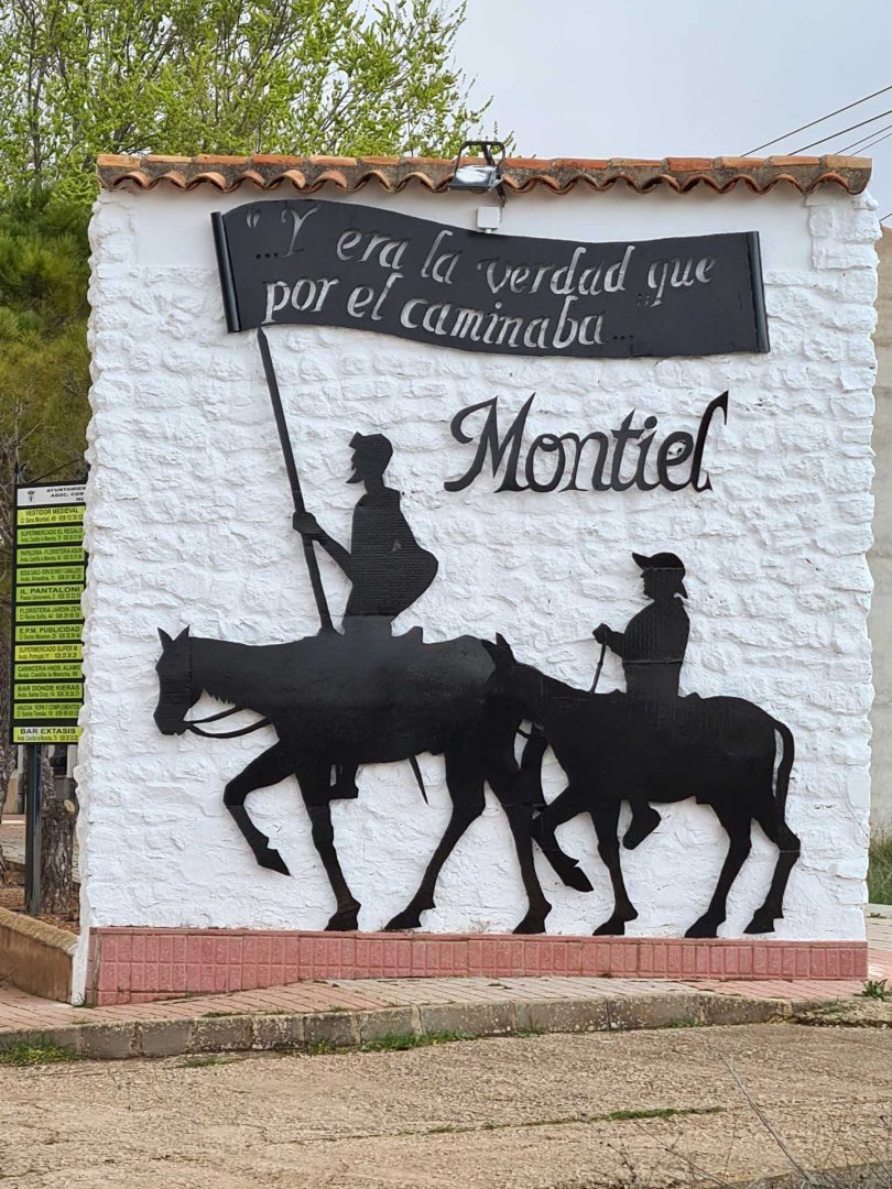 Wandbild mit Don Quijote hoch zu Ross und Sancho Panza auf seinem Esel, dazu das Zitat ‚Y era la verdad que por él caminaba‘ – Wohnmobil-Rundreise Spanien
