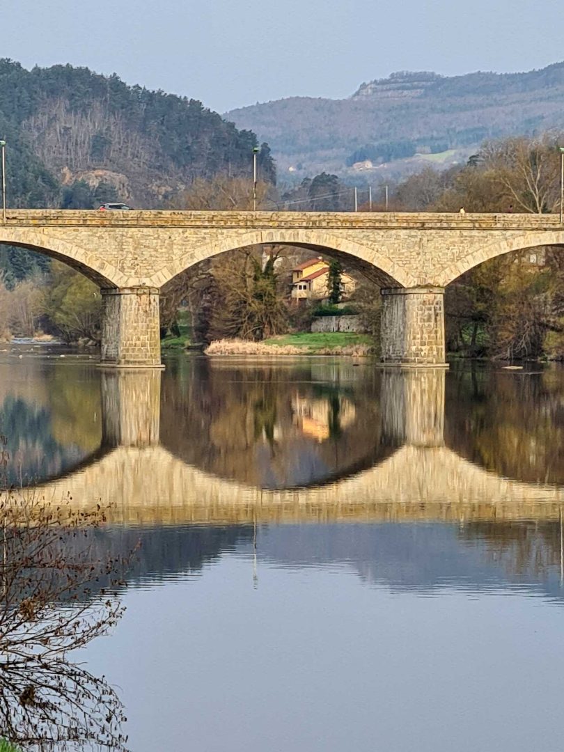Römische Brücke in Frankreich spiegelt sich vollständig im Fluss und bildet ein perfektes Doppelbild – Wohnmobil-Rundreise Spanien