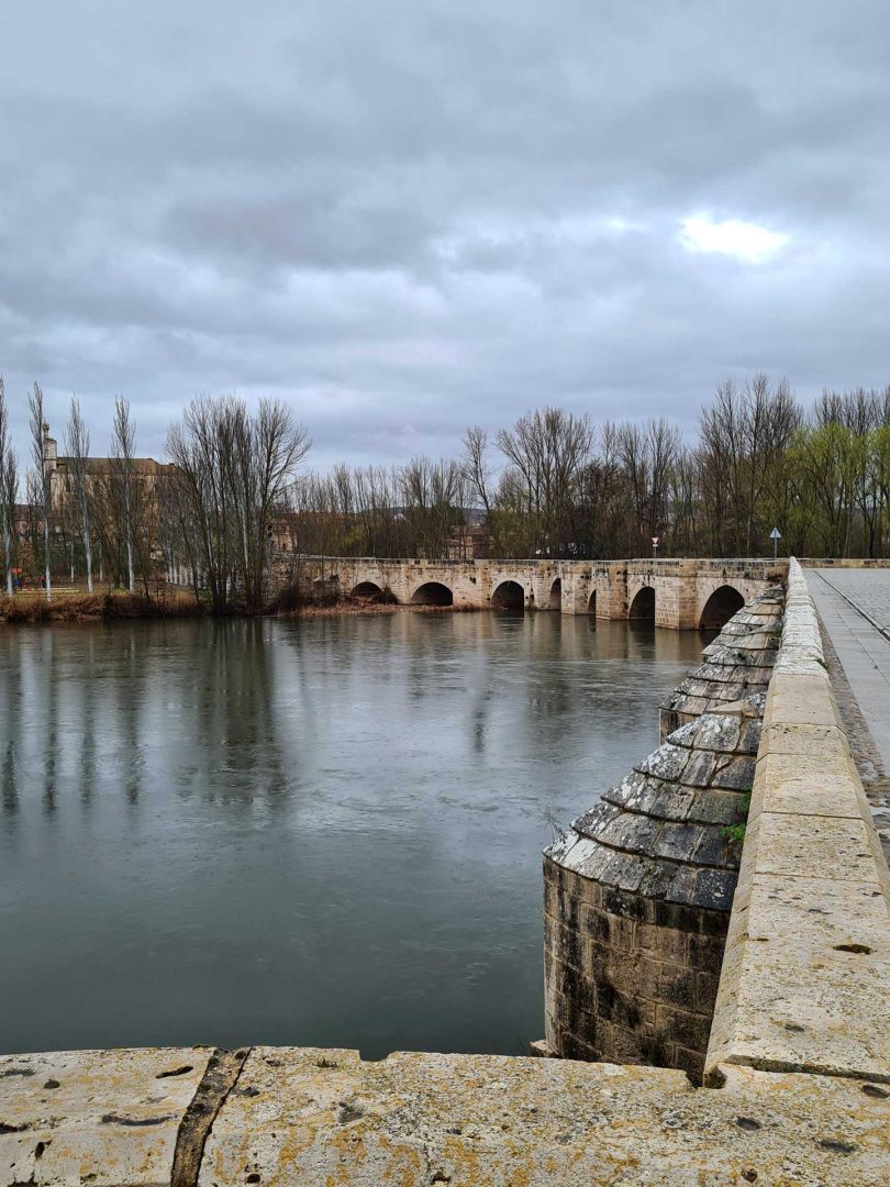 Torquemada-Brücke im Regen mit nasser Straße und dunklen Wolken - Wohnmobil-Rundreise Spanien